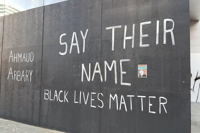 Black wall with Ahmaud Arbary, Say Their Name & Black Lives Matter written on it